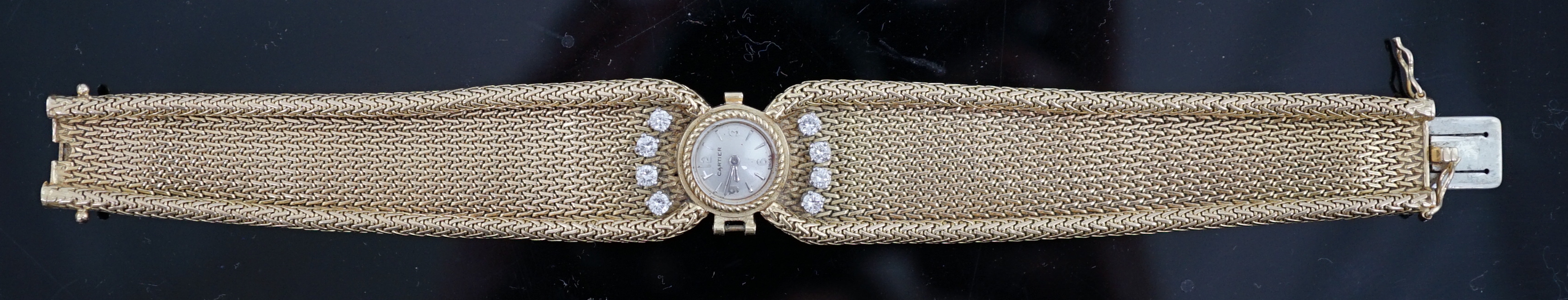 A lady's 18ct gold and eight stone diamond set manual wind cocktail, the dial inscribed Cartier, on integral tapered gold bracelet set with eight round cut stones